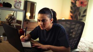 Junge Frau lernt am Laptop und macht Notizen zur Weiterbildung