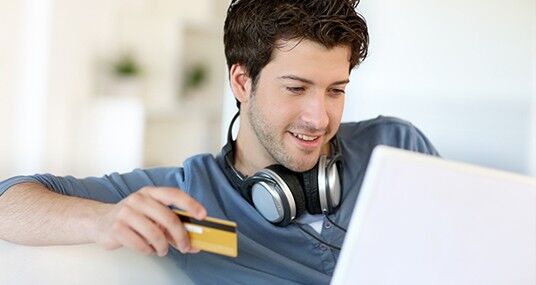 young man with credit card headphones laptop mst 1