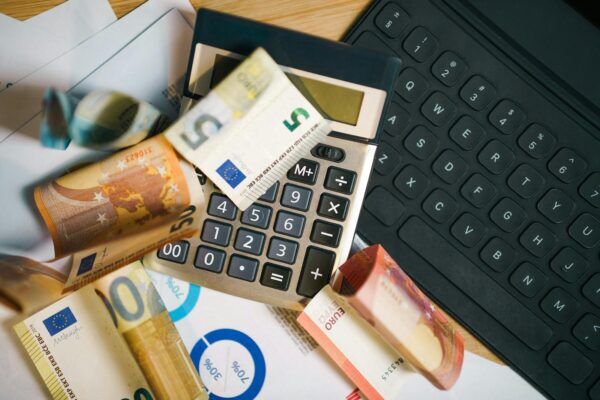Euro-Banknoten, Rechner und Laptop als Symbol für Lohntransparenz und Gehaltsplanung in Österreich